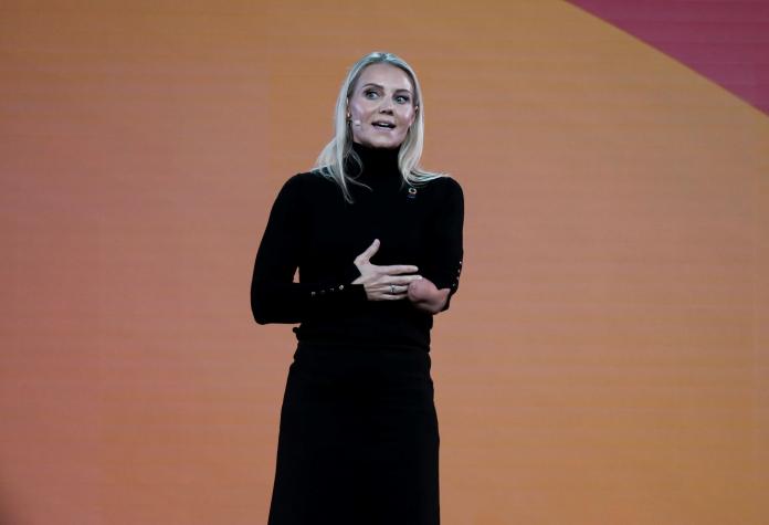 Jessica Smith makes a speech in front of a orange banner