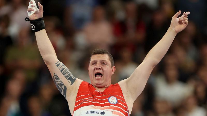 A male athlete opens his arms widely to celebrate