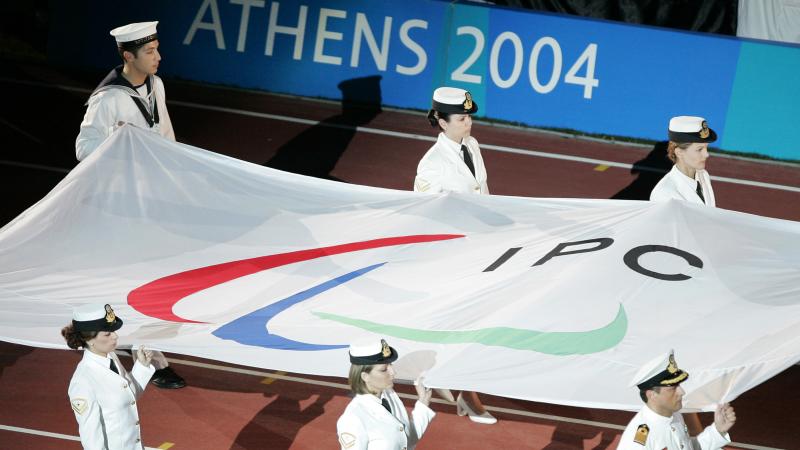 Closing Ceremony of the Athens 2004 Paralympic Games Six people carry a flag with the Paralympic symbol into a stadium