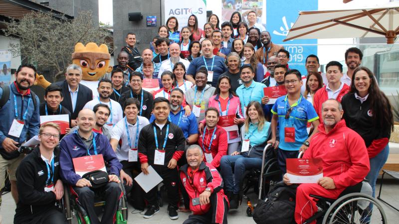 Road to Lima 2019 - Agitos Foundation a group of people and the Lima 2019 mascot smile for a photo