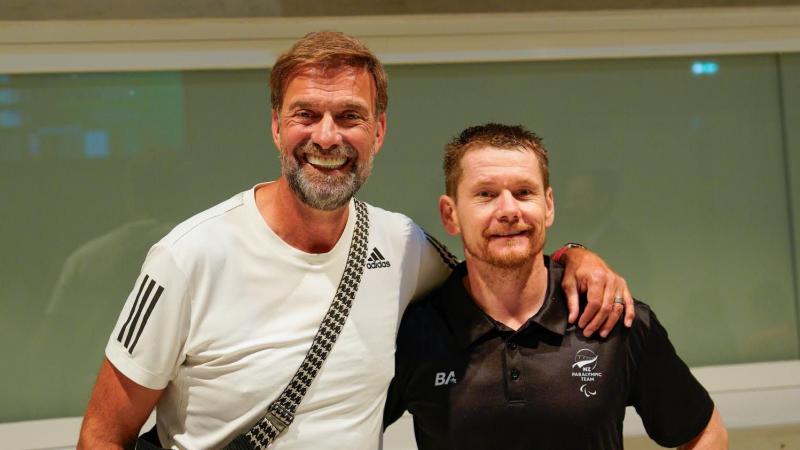 Man in a white tee with his arm round man in a black tee 