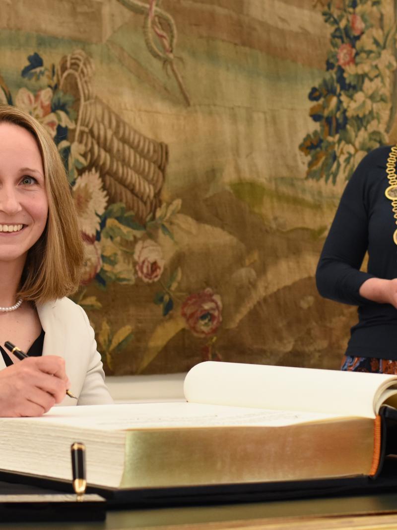 Annika Zeyen signs the Golden Book of Bonn as Bonn Mayor smiles behind