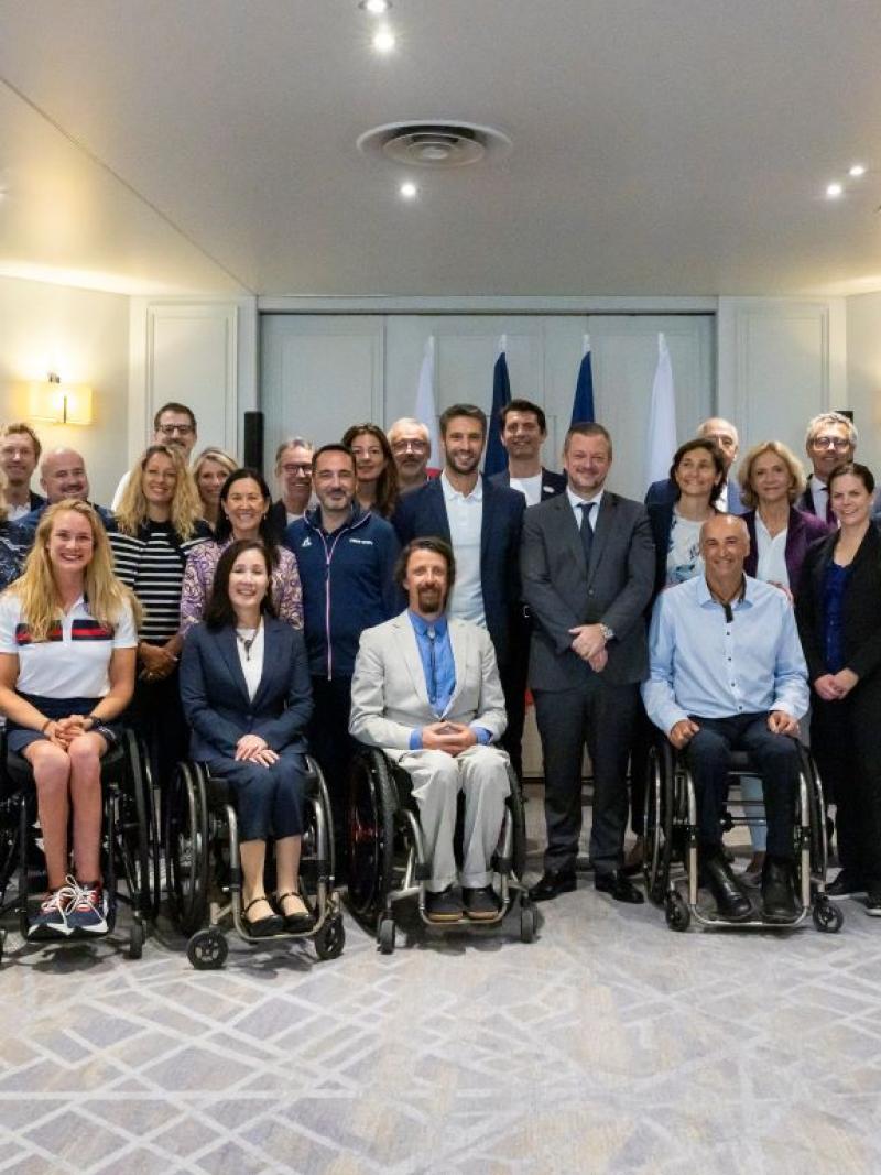 A group of people both standing and in wheelchairs smile together