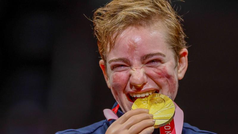 A female athlete bites a gold medal