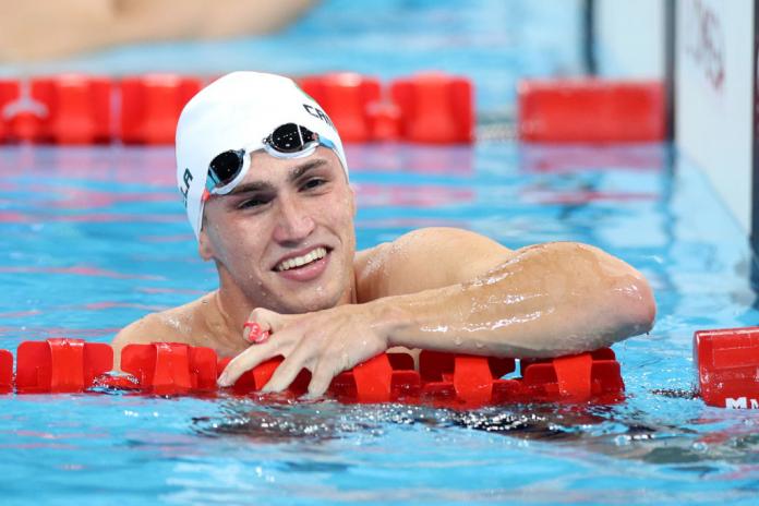 A male Para swimmer smiles in the pool after his race