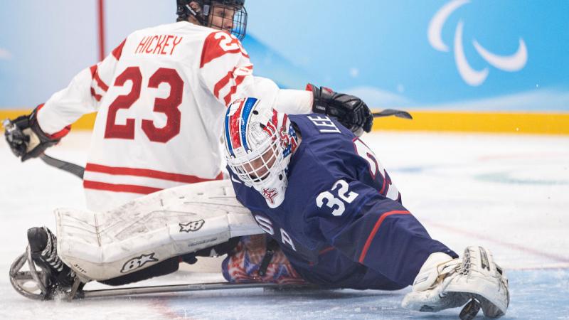 A Para ice hockey goaltender making a save in front of an opponent