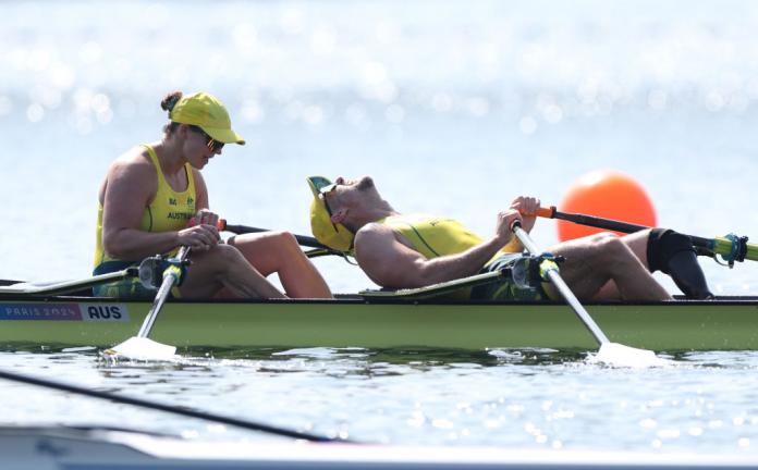 Two Australian rowers, dressed in yellow, look exhausted after winning gold in Paris