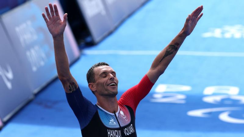 Para triathlete Alexis Hanquinquant raising his arms in celebration at the finish line