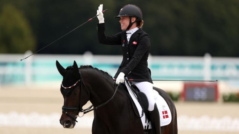 Para equestrian rider Katrine Kristensen smiles and waves on her horse