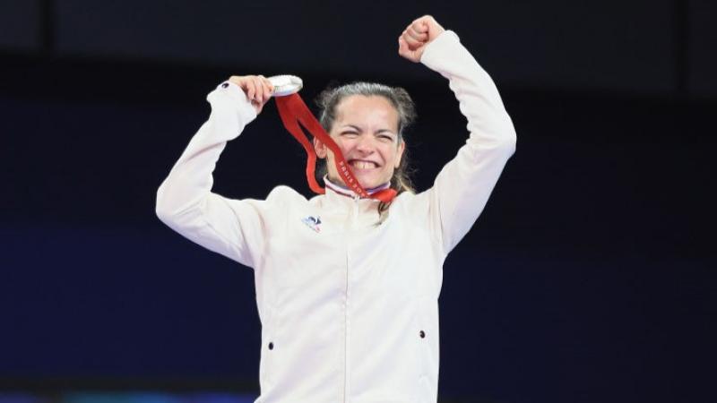 Para judoka Sandrine Martinet holding up a silver medal and smiling