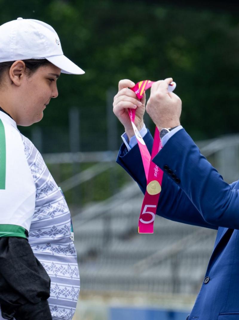 A man wearing a blue suit presents a medal to a female athlete.