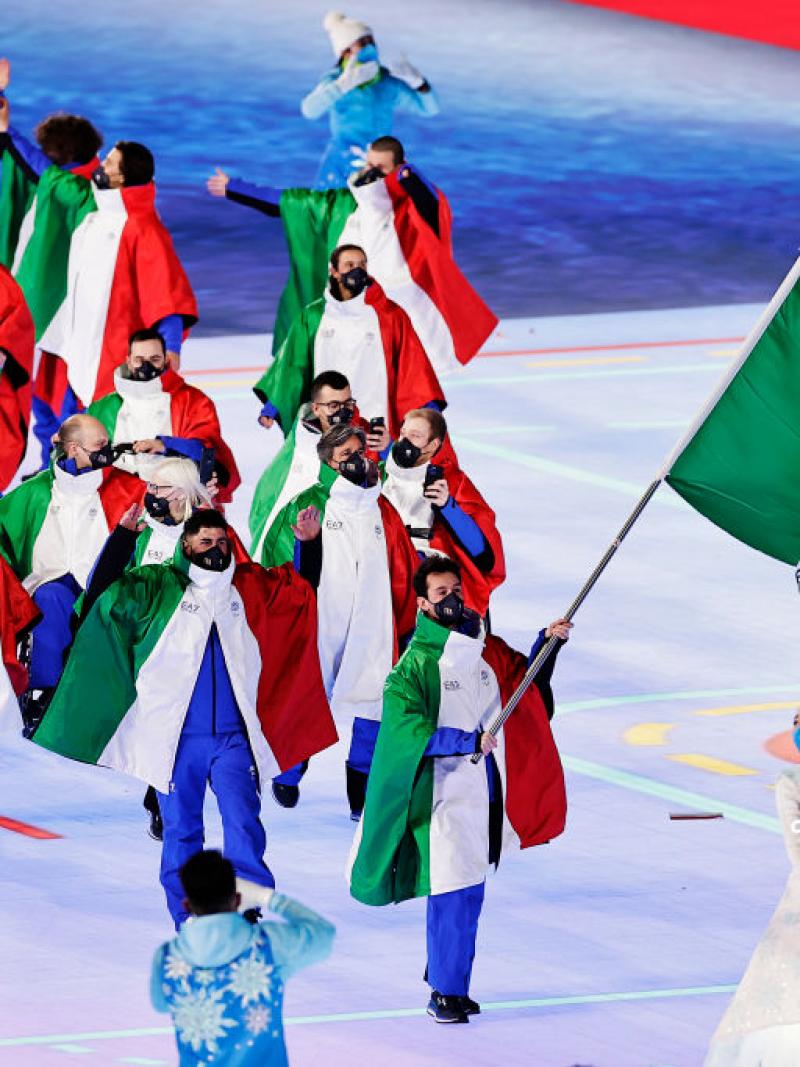 A group of about 15 athletes dressed in Italy's uniform march into the Opening Ceremony of the Beijing 2022 Paralympic Games.