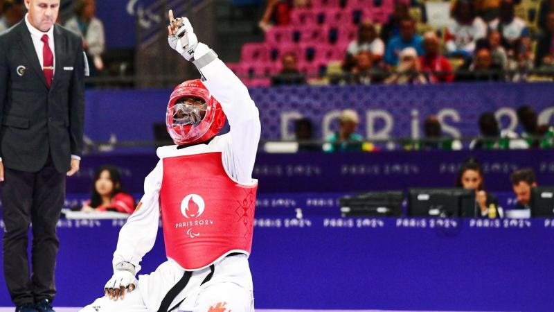 Para taekwondo fighter Idrissa Keita kneeling and pointing to the sky in celebration 