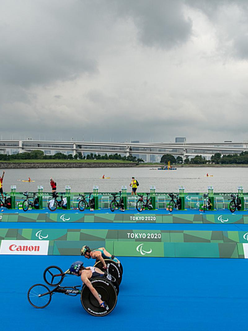 Two wheelchair racers neck-in-neck down home stretch