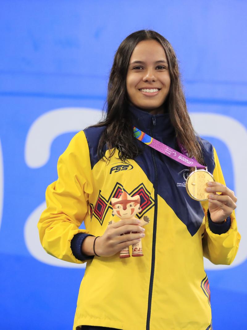 female Para swimmer on the podium holding her gold medal