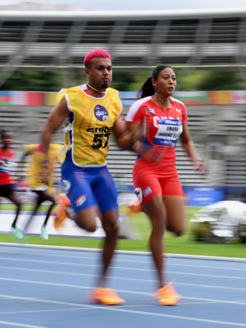 A female sprinter and her male guide race. They are in front of a pack of athletes.
