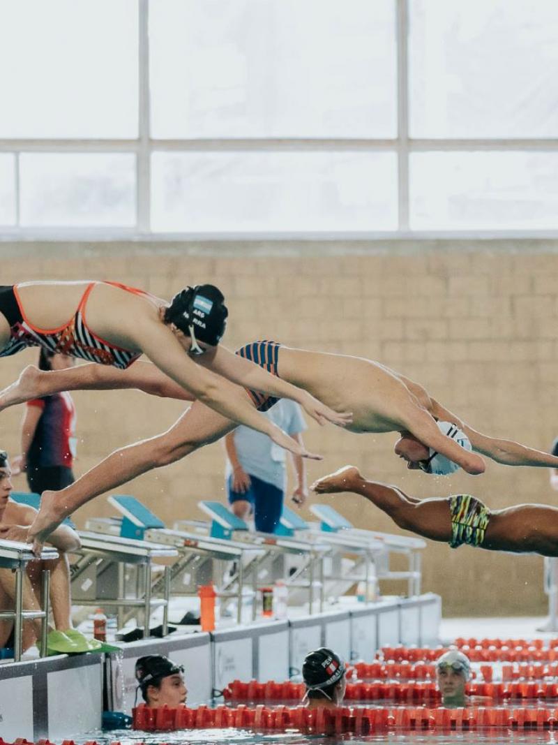 Three Para swimmers jump into the pool