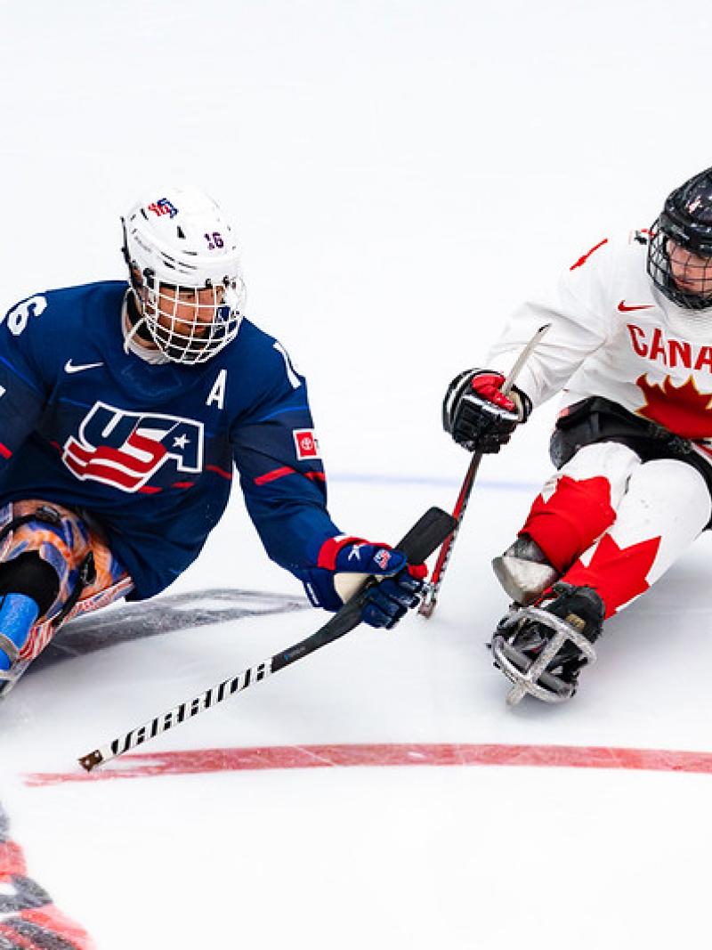 Two Para ice hockey players from USA and Canada in a game